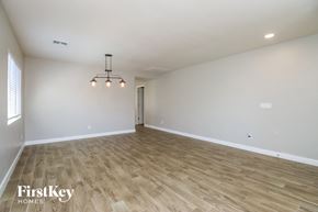 Youngtown house for rent - A spacious room with wooden flooring and a chandelier.