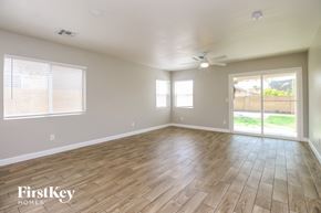 Youngtown house for rent - A spacious room with wooden flooring and a sliding glass door leading to a backyard.