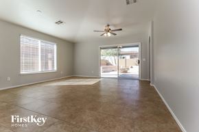 Surprise house for rent - an empty living room with a ceiling fan and a door to a patio
