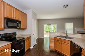 Huntersville house for rent - a kitchen with wooden cabinets and a black stove and a sink