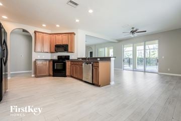 North Port house for rent - an open kitchen and living room with wooden cabinets and appliances and a ceiling fan