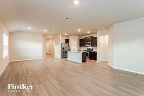San Antonio house for rent - A spacious, empty room with wooden floors and a kitchen area in the background.