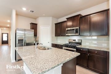 San Antonio house for rent - A kitchen with granite countertops and dark brown cabinets.