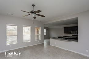 Glenn Heights house for rent - an empty living room with a ceiling fan and a kitchen