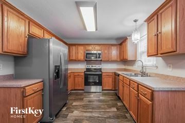 Monroe house for rent - a kitchen with wooden cabinets and a stainless steel refrigerator