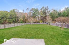 Monroe house for rent - a backyard with green grass and a fence and trees
