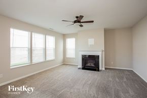 Noblesville house for rent - A spacious living room with a fireplace and a ceiling fan.