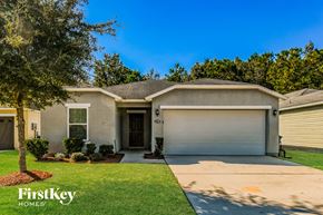 Jacksonville house for rent - A house with a garage door and a tree in front of it.