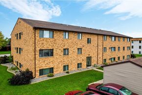 Fargo apartment for rent - A large brick building with a green lawn in front.