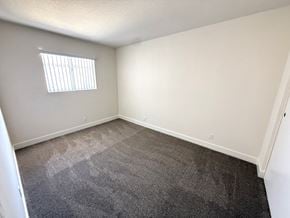 Anaheim apartment for rent - A room with a carpeted floor and a window with blinds.