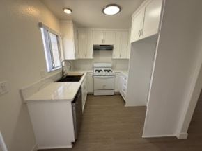 Anaheim apartment for rent - A white kitchen with a dishwasher and a stove top oven.
