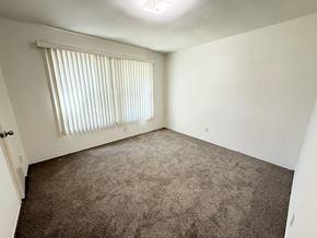 Anaheim apartment for rent - A room with a carpeted floor and a window with blinds.