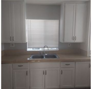 San Bernardino apartment for rent - a kitchen with white cabinets and a sink and a window