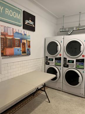 Astoria apartment for rent - A laundromat with a row of washers and a bench.