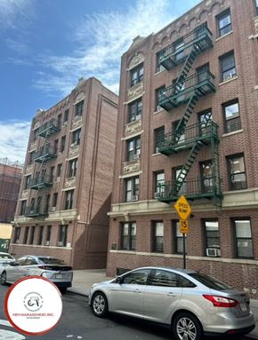 Astoria apartment for rent - A silver car is parked on the street in front of a brick building with a green fire escape.