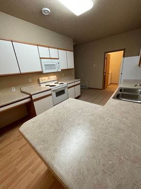 Fargo apartment for rent - an empty kitchen with white cabinets and stainless steel appliances
