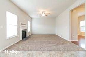 Clayton house for rent - a empty living room with a fireplace and a ceiling fan
