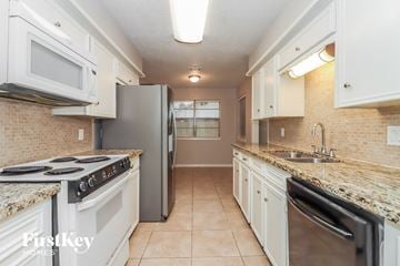 Baytown house for rent - a kitchen with white cabinets and stainless steel appliances