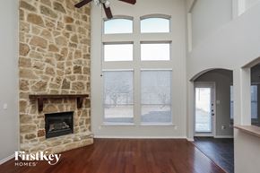 Rowlett house for rent - A stone fireplace in a room with a wood floor and a ceiling fan.