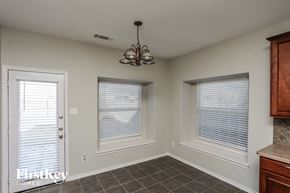 Rowlett house for rent - A room with a chandelier, two windows with blinds, and a door with a window.