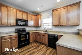 Holly Springs house for rent - a kitchen with wooden cabinets and black appliances