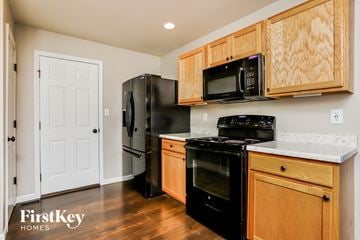 St Peters house for rent - a kitchen with black appliances and wooden cabinets and a black refrigerator