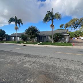 National City apartment for rent - A street view with a building and palm trees.