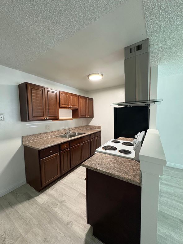 National City apartment for rent - A kitchen with brown cabinets and a granite countertop.