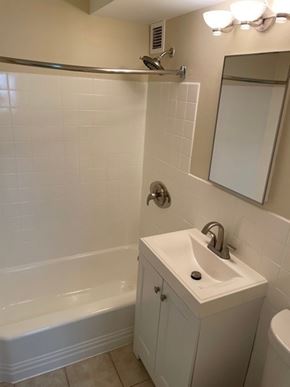St. Louis apartment for rent - A white bathroom with a tub, sink, and mirror.