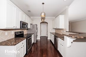 Trussville house for rent - a large kitchen with white cabinets and granite counter tops