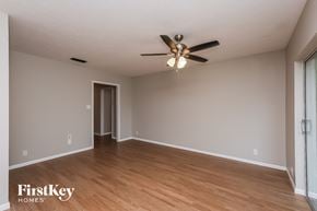 Brandon house for rent - an empty living room with a ceiling fan and wood floors