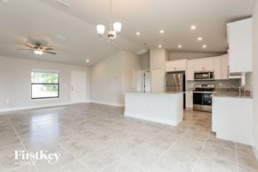 Lehigh Acres house for rent - an open kitchen and living room with white cabinets and tile flooring