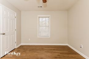 Newnan house for rent - a bedroom with a wooden floor and a window and a white door