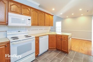Winston Salem house for rent - a kitchen with white appliances and wooden cabinets