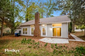 Mint Hill house for rent - A house with a brown door and a chimney is surrounded by trees.