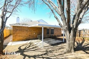 Mansfield house for rent - A house with a brick exterior and a white roof is surrounded by bare trees.