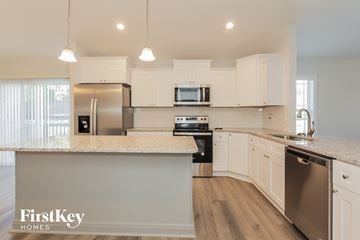 Kannapolis house for rent - a kitchen with white cabinets and a marble counter top