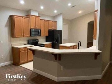 Wesley Chapel house for rent - A kitchen with wooden cabinets and a black refrigerator.