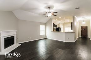 Haslet house for rent - A spacious living room with a fireplace and a ceiling fan.