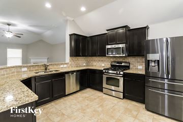 Haslet house for rent - A kitchen with black cabinets and stainless steel appliances.
