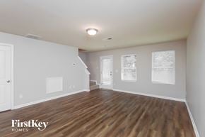 Conyers house for rent - A spacious room with wooden floors and white walls, branded with "FirstKey Homes".