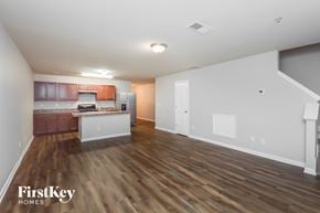Conyers house for rent - A spacious living room with wooden floors and a kitchen area in the background.