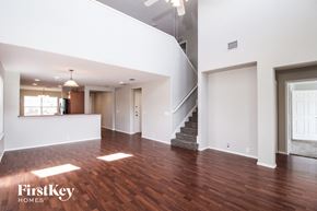 Fort Worth house for rent - A spacious living room with wood flooring and a staircase leading to another level.