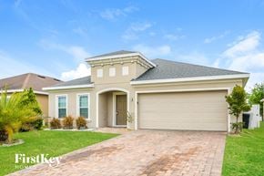 Kissimmee house for rent - a beige house with a garage door and a lawn