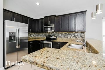 Kissimmee house for rent - a kitchen with granite counter tops and black cabinets