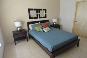 Minneapolis apartment for rent - A bed with a blue comforter and a lamp on a side table.