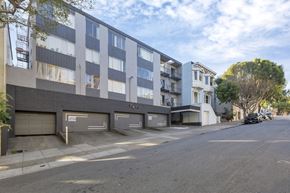 San Francisco apartment for rent - A street view of a residential area with apartment buildings and cars parked on the side of the road.