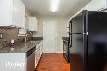 Newnan house for rent - a kitchen with white cabinets and black appliances and a black refrigerator