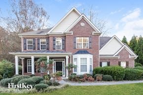 Mableton house for rent - A brick house with a white porch and a sign that says "FirstKey Homes".