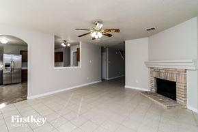 Fort Worth house for rent - A spacious living room with a fireplace and a ceiling fan.